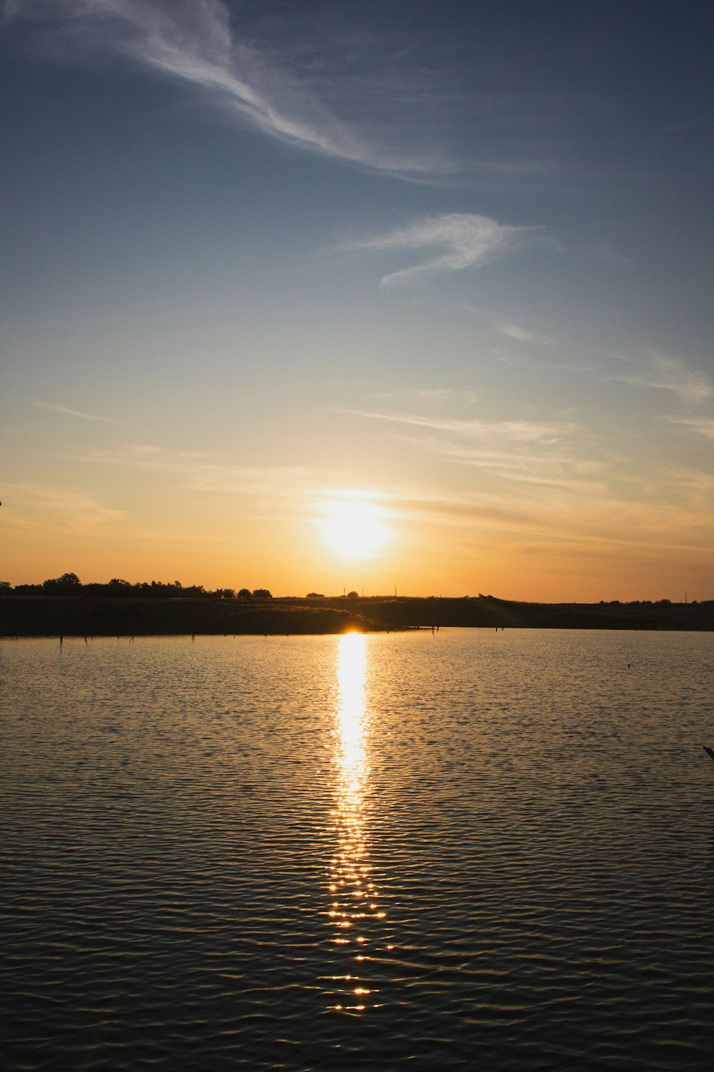 a large body of water with a sunset in the background