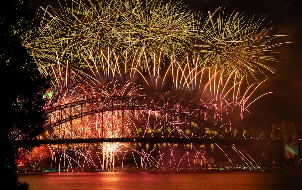 a large fireworks display over a bridge over water