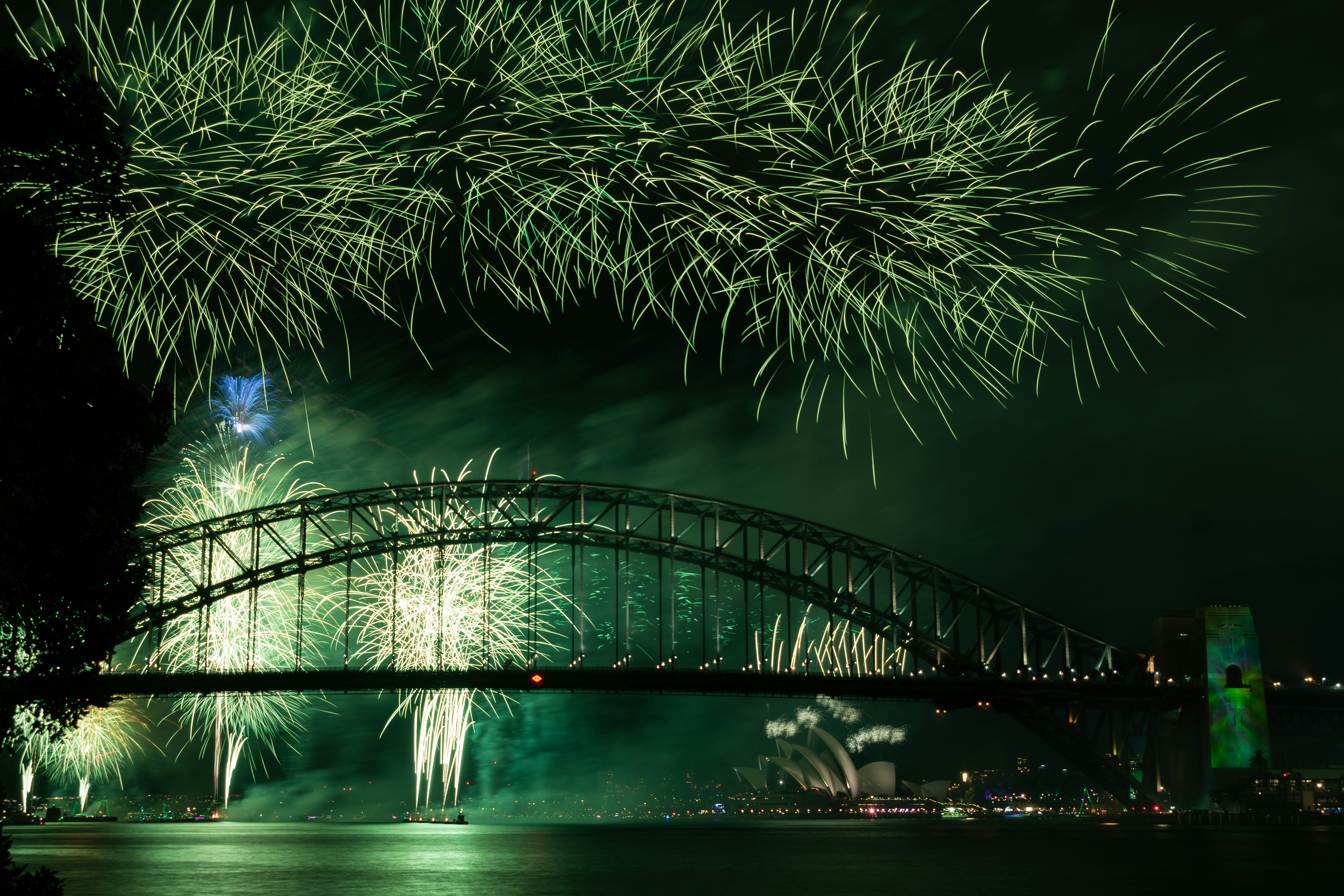 fireworks are lit up in the night sky over a bridge