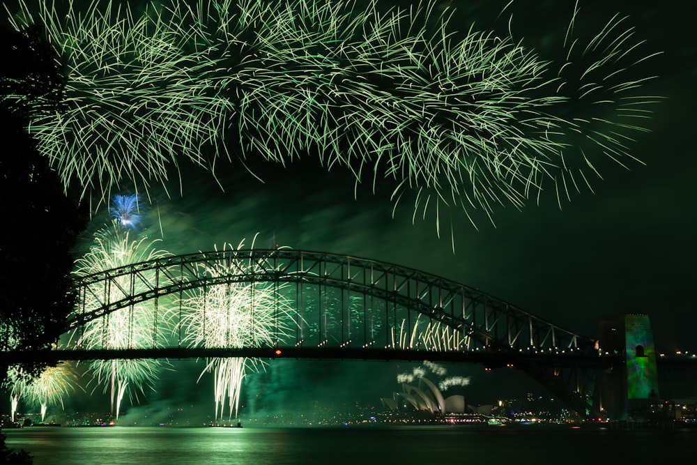 fireworks are lit up in the night sky over a bridge