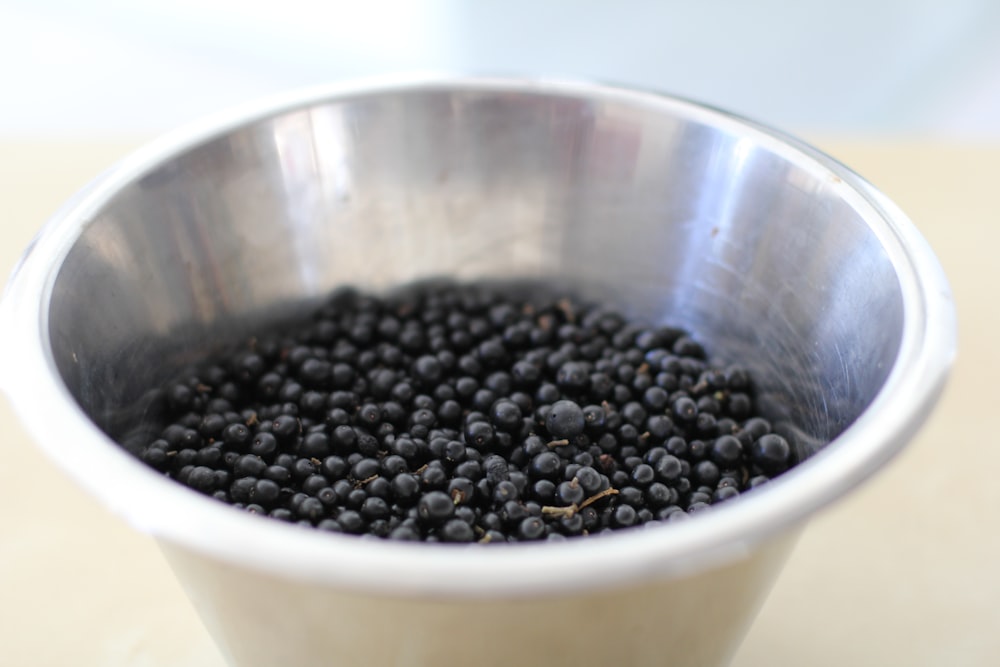 a metal bowl filled with blackberries on a table