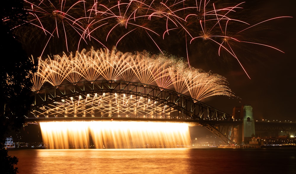 fireworks are lit up in the sky above a bridge