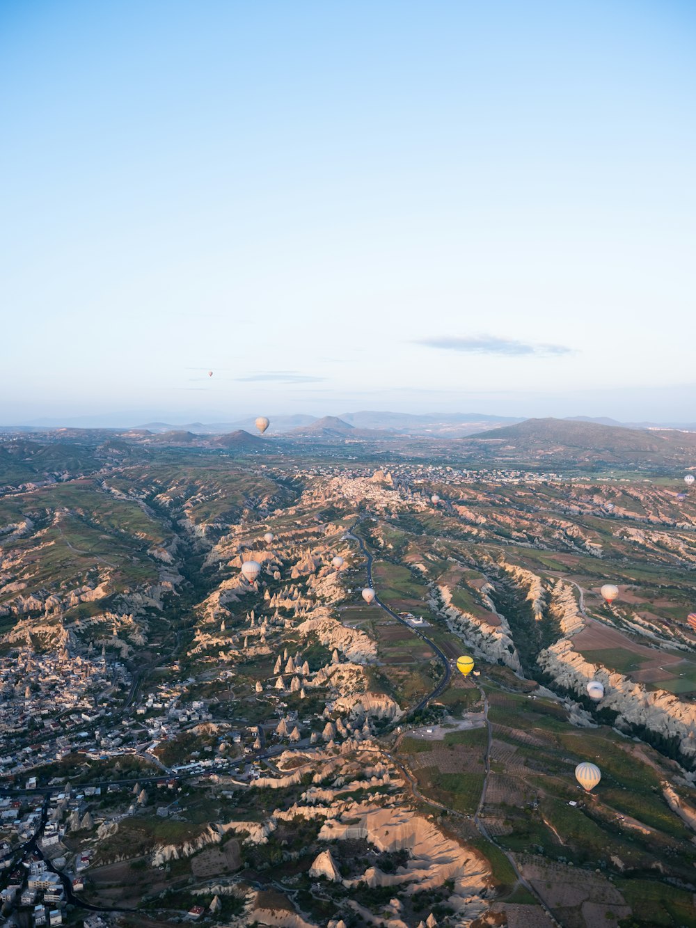 a hot air balloon flying over a valley