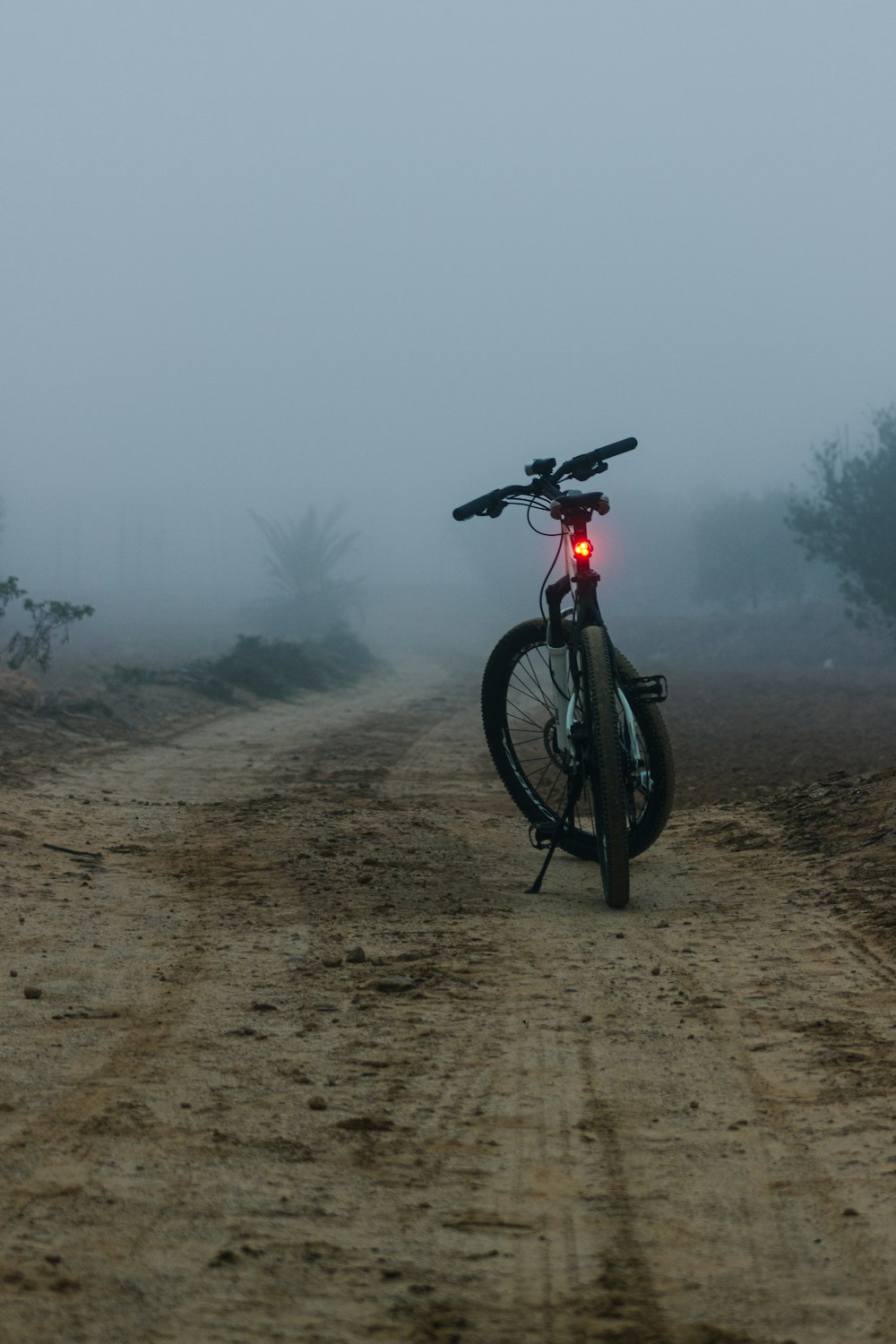 霧のかかった未舗装の道路に自転車が停まっている