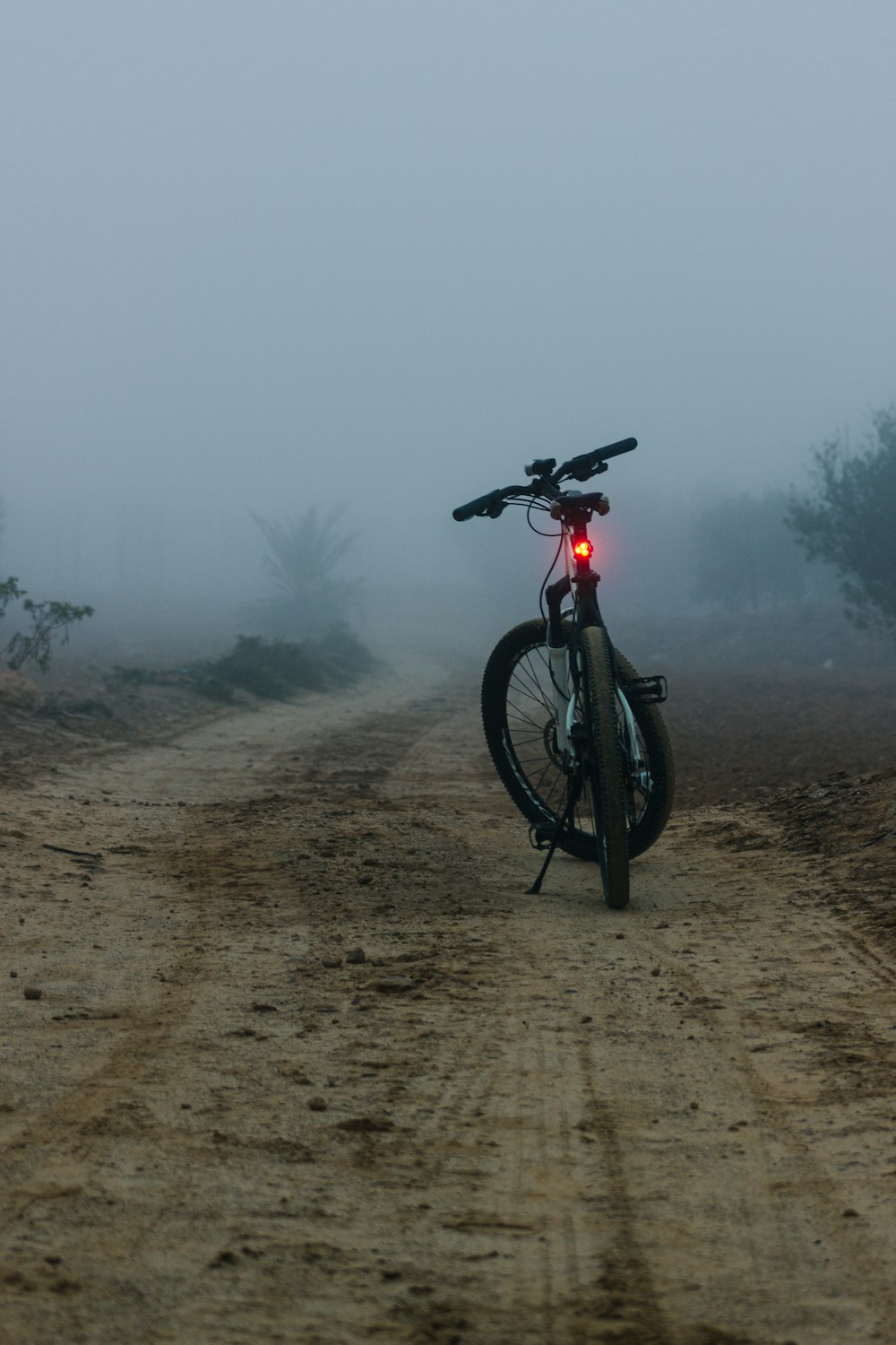 a bicycle is parked on a foggy dirt road