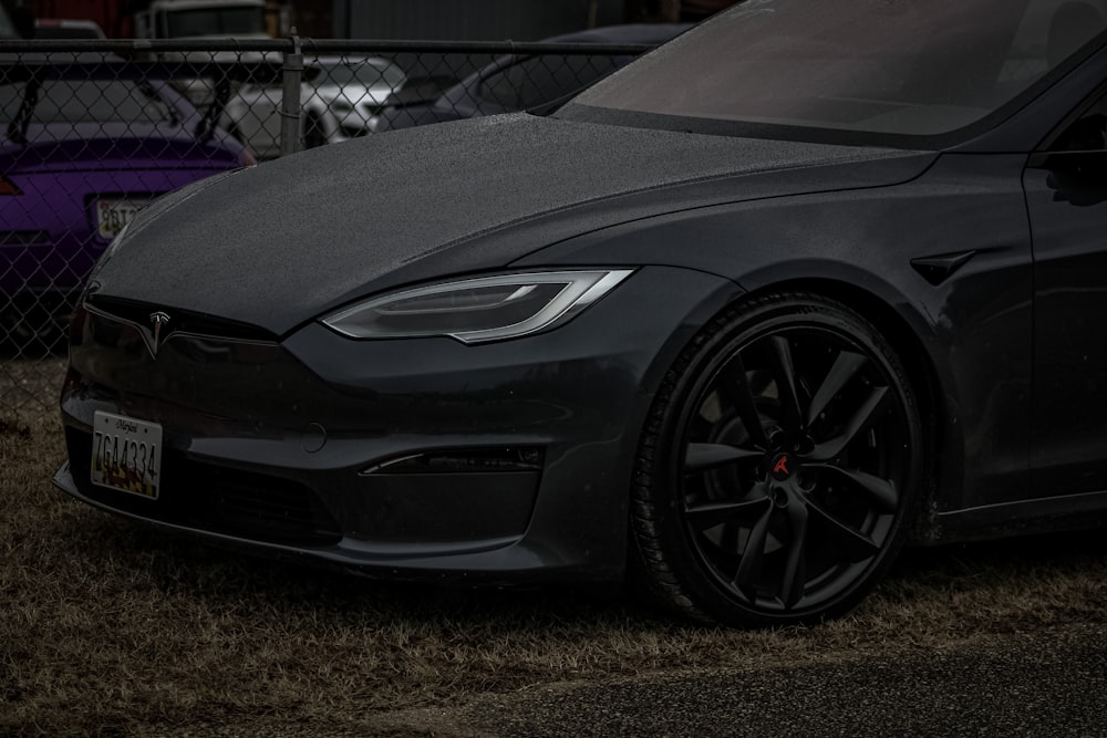 a black car parked in front of a fence