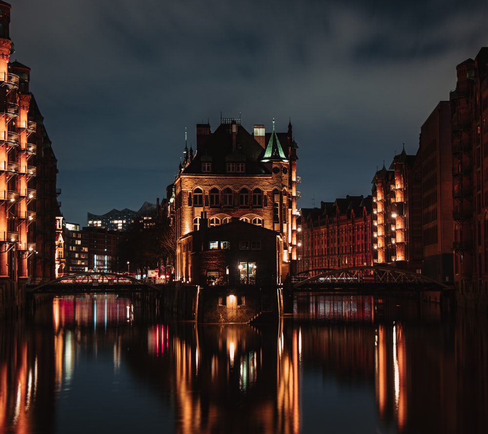 a night scene of a city with a bridge and buildings