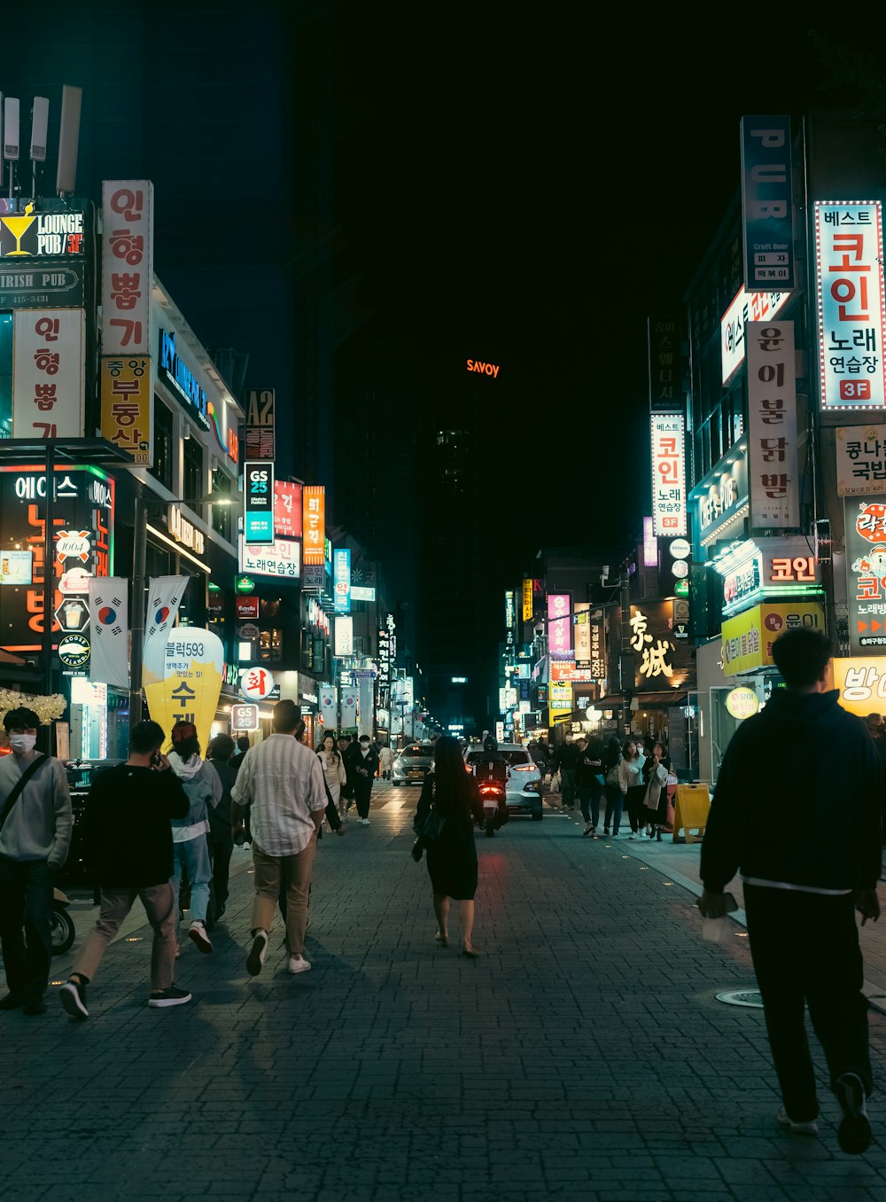 a group of people walking down a street at night