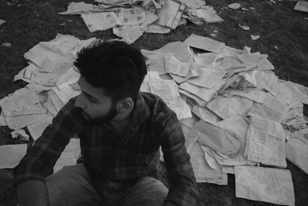 a man sitting on the ground surrounded by papers