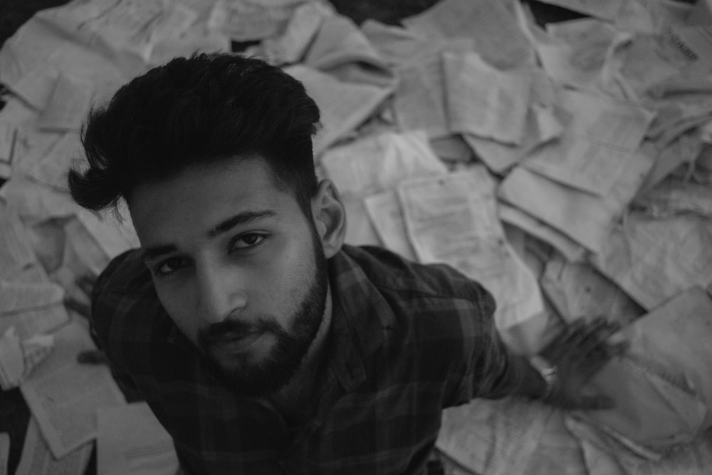 a man with a beard standing in front of a pile of papers