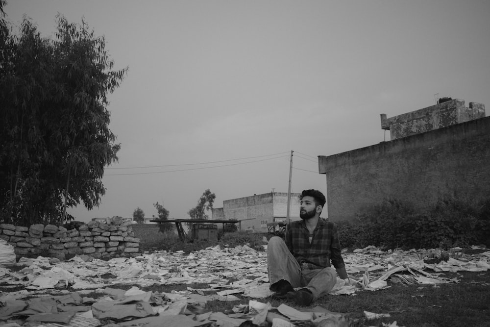 a man sitting on the ground surrounded by trash
