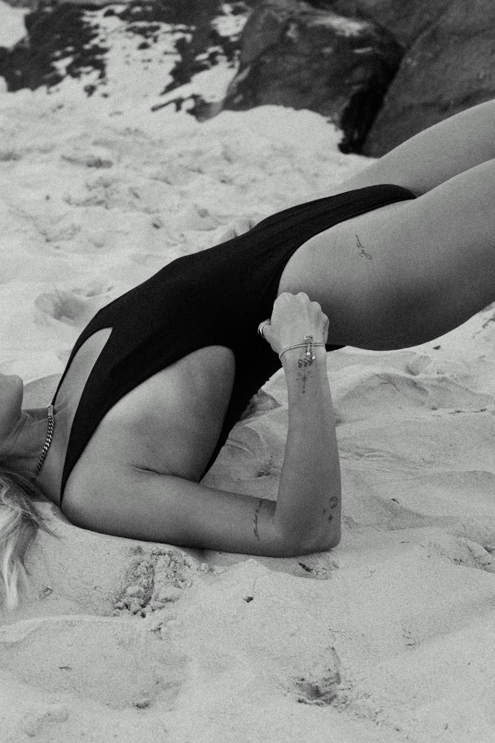 수영복을 입은 여자가 모래 위에 누워 있다