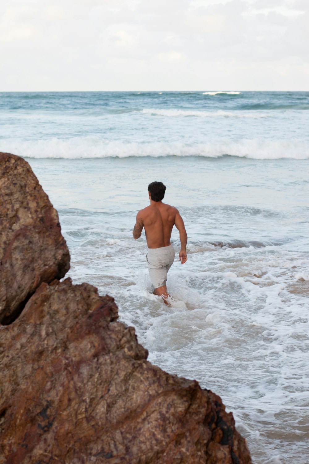 um homem saindo do oceano com uma prancha de surfe