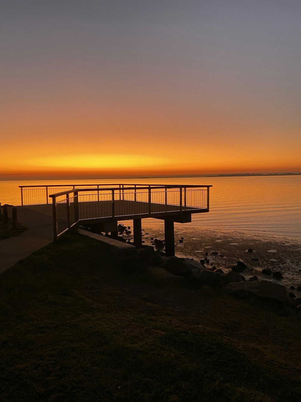a wooden bridge over a body of water at sunset