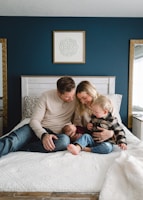 a man, woman, and child sitting on a bed