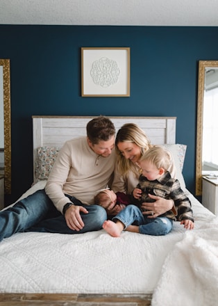 a man, woman, and child sitting on a bed