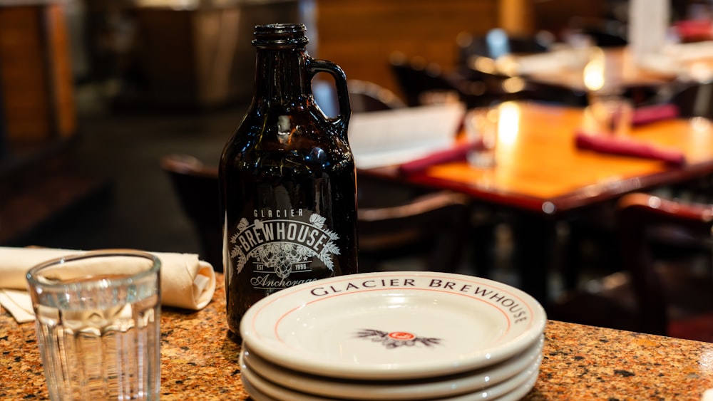 a bottle of beer sitting next to a stack of plates