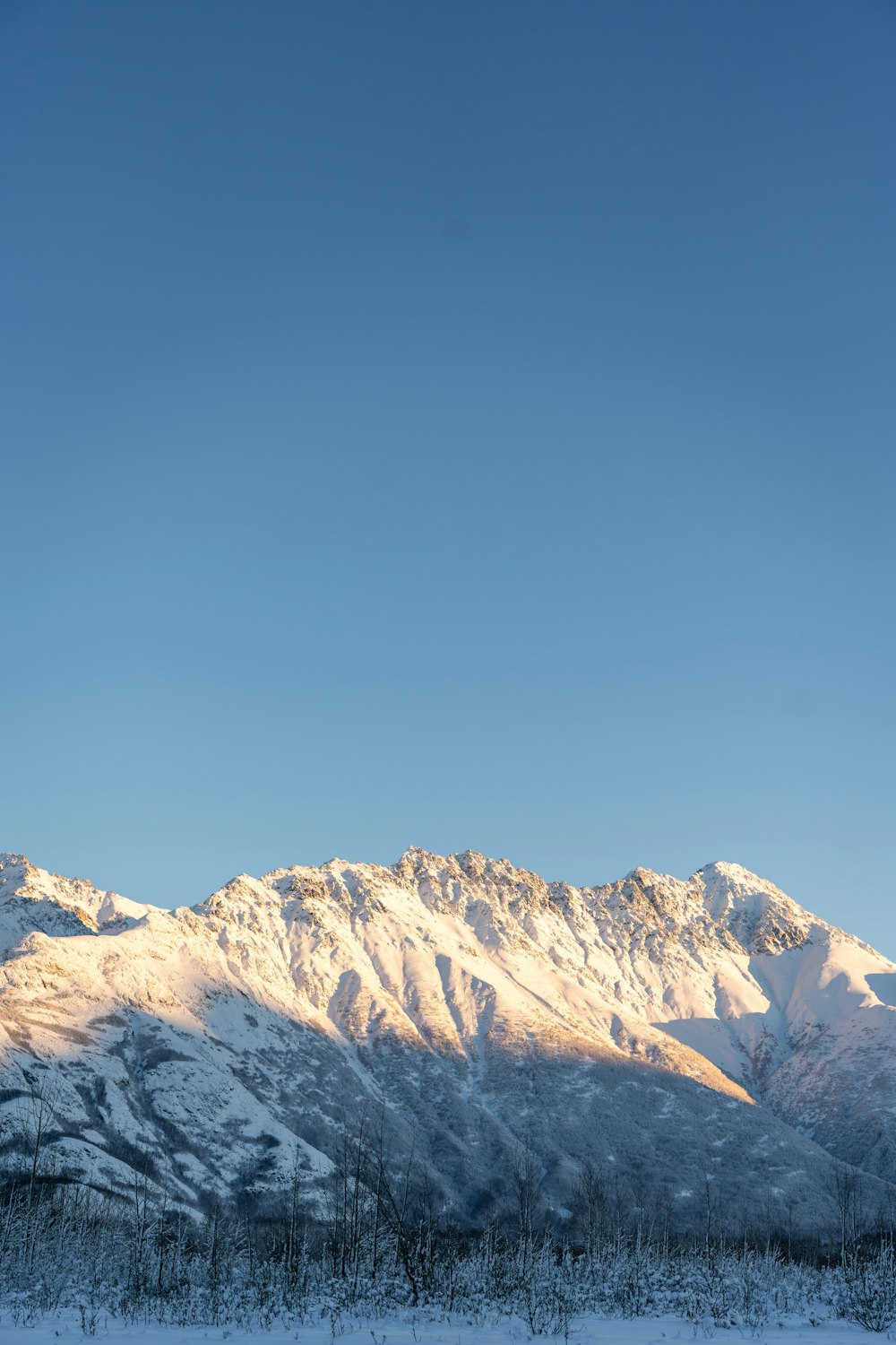 a snow covered mountain range with a clear blue sky