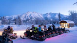 a group of people riding snowmobiles in the snow