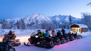 a group of people riding snowmobiles in the snow