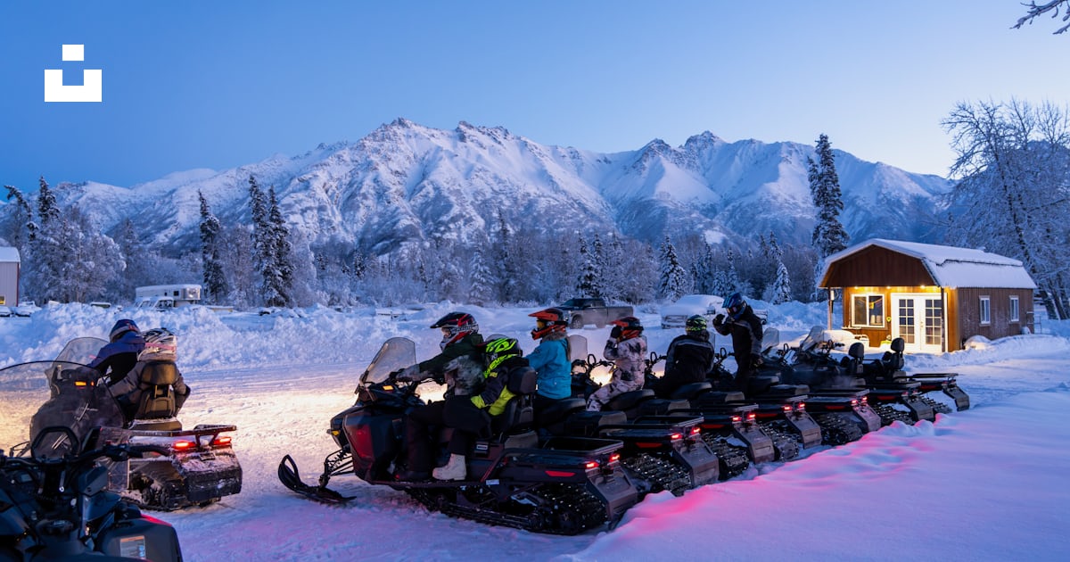 A group of people riding snowmobiles in the snow photo – Free Alaska ...