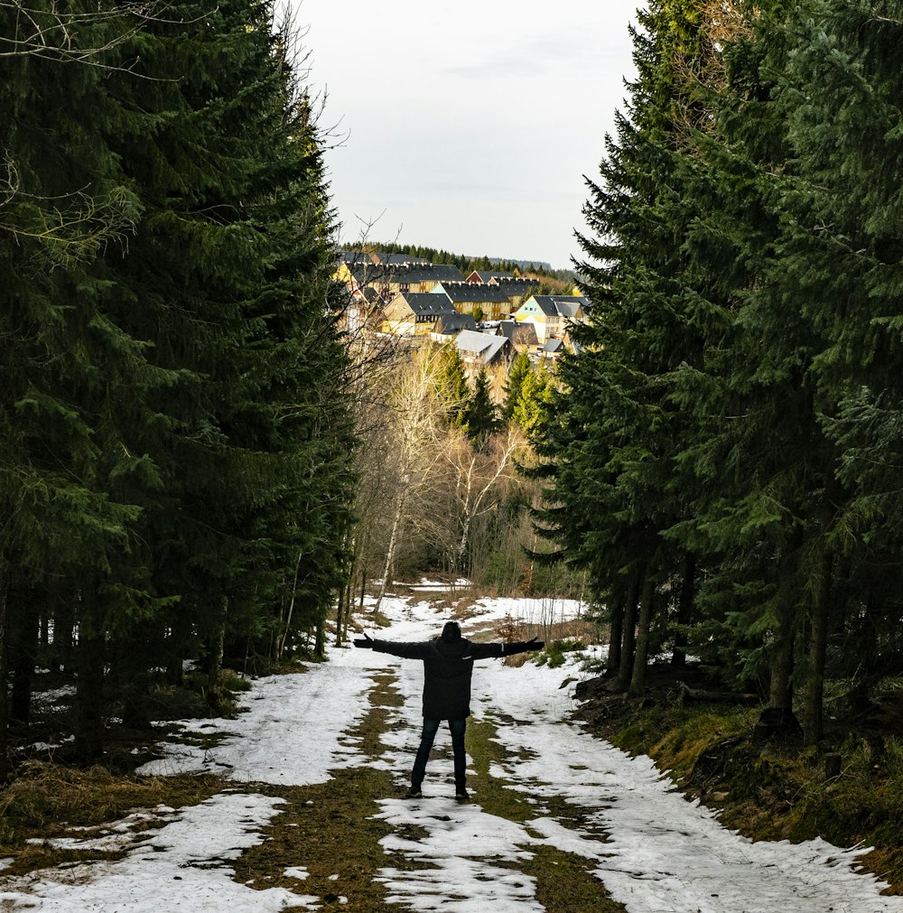 a man standing in the middle of a snow covered road