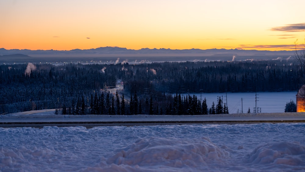 the sun is setting over a snowy landscape