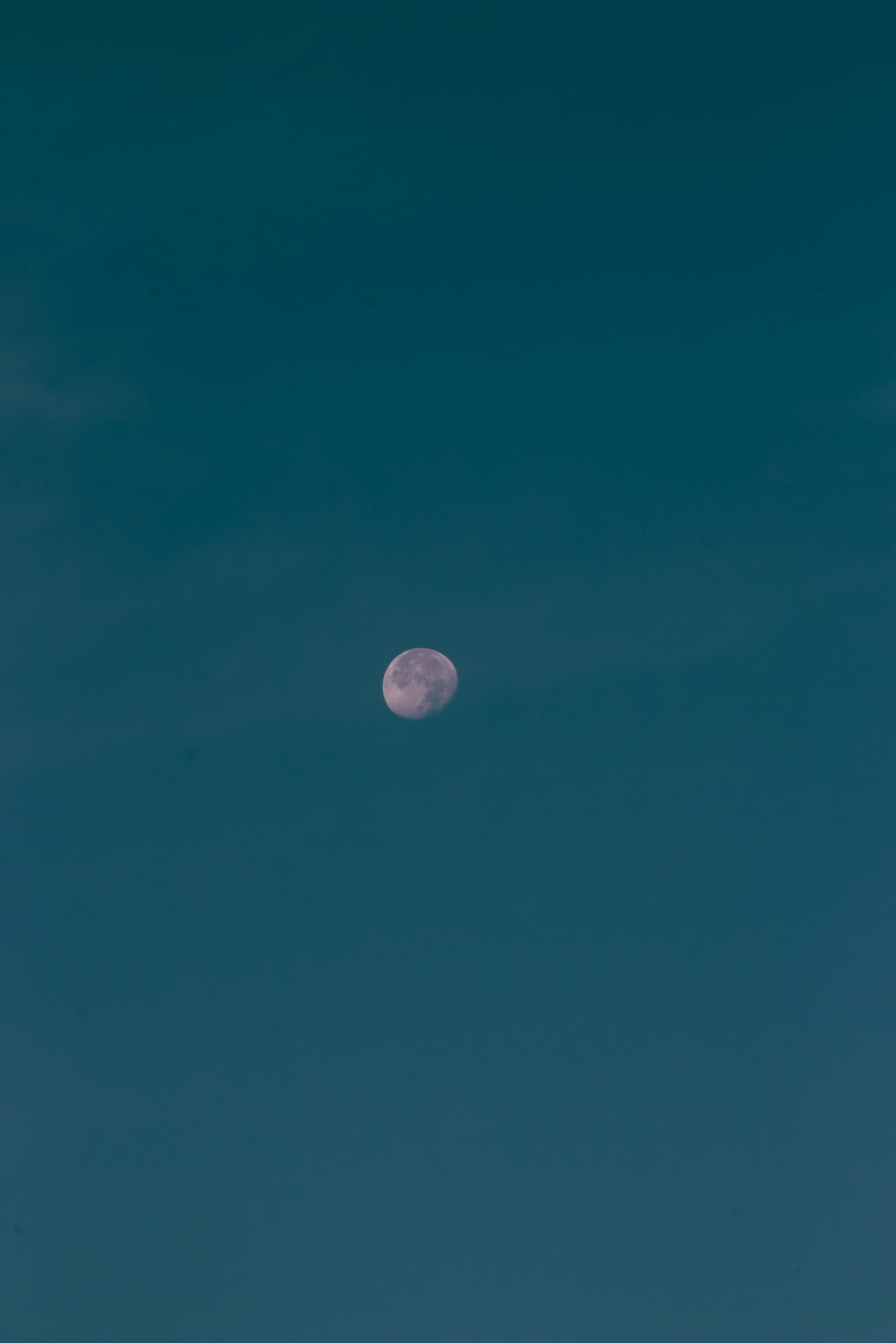 a clear blue sky with a half moon in the distance