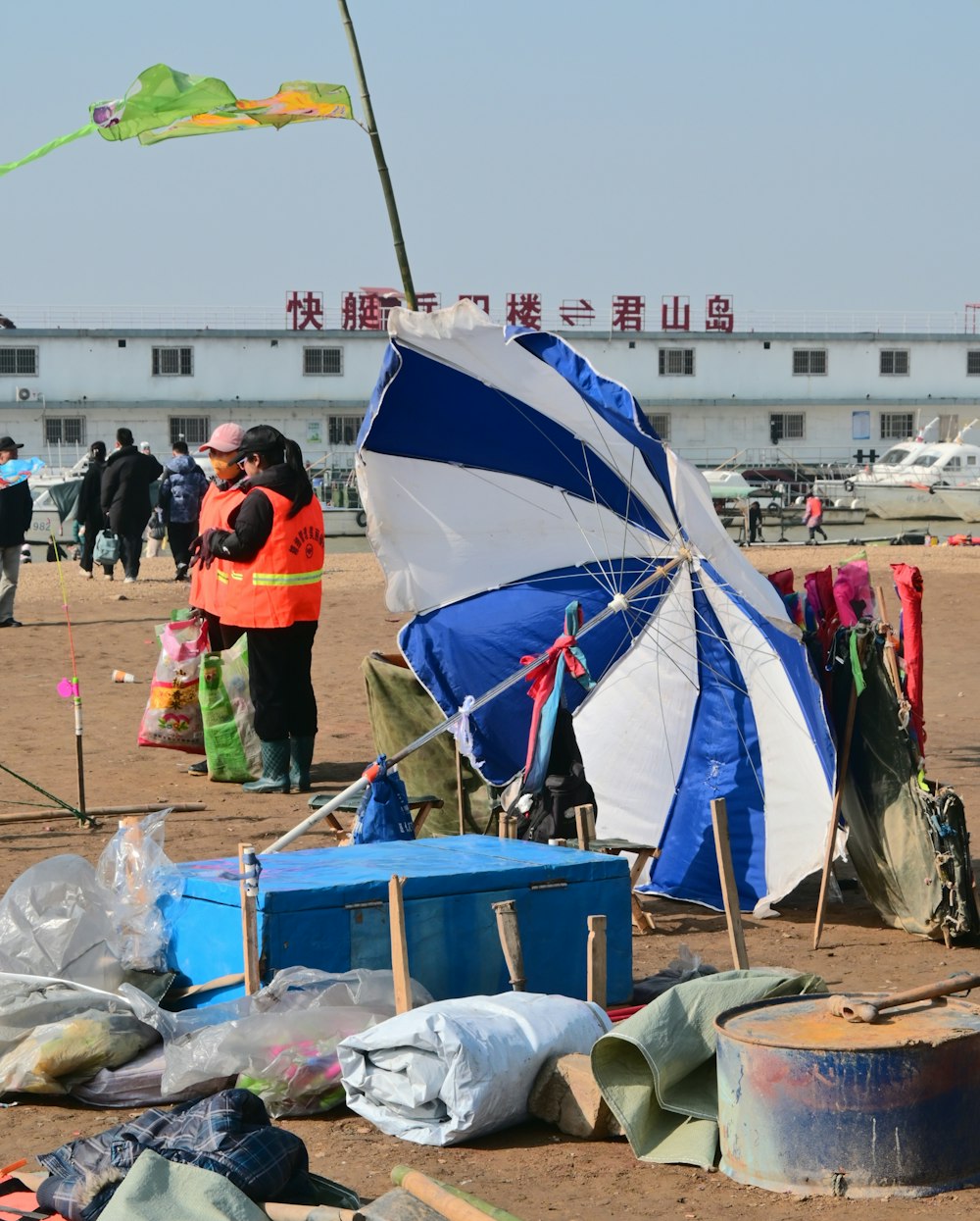 a group of people standing around a blue and white umbrella