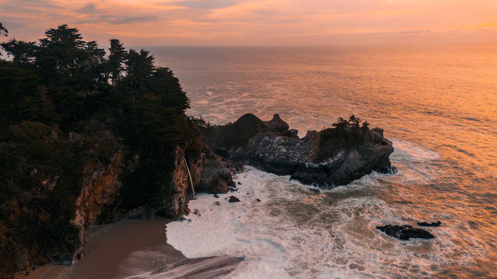 an aerial view of the ocean with a sunset in the background