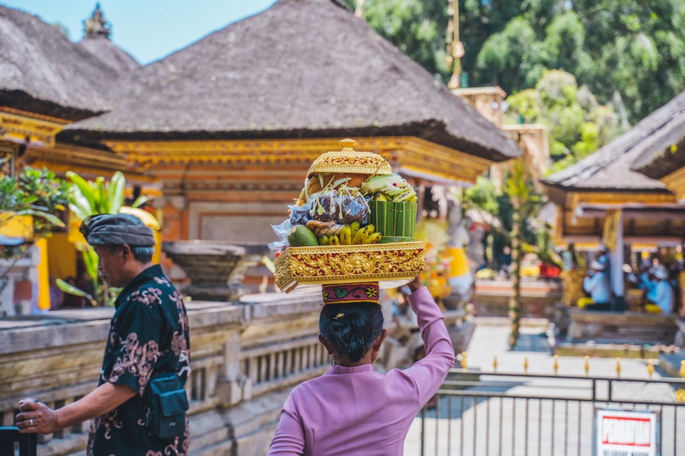 a woman carrying a basket of fruit on her head