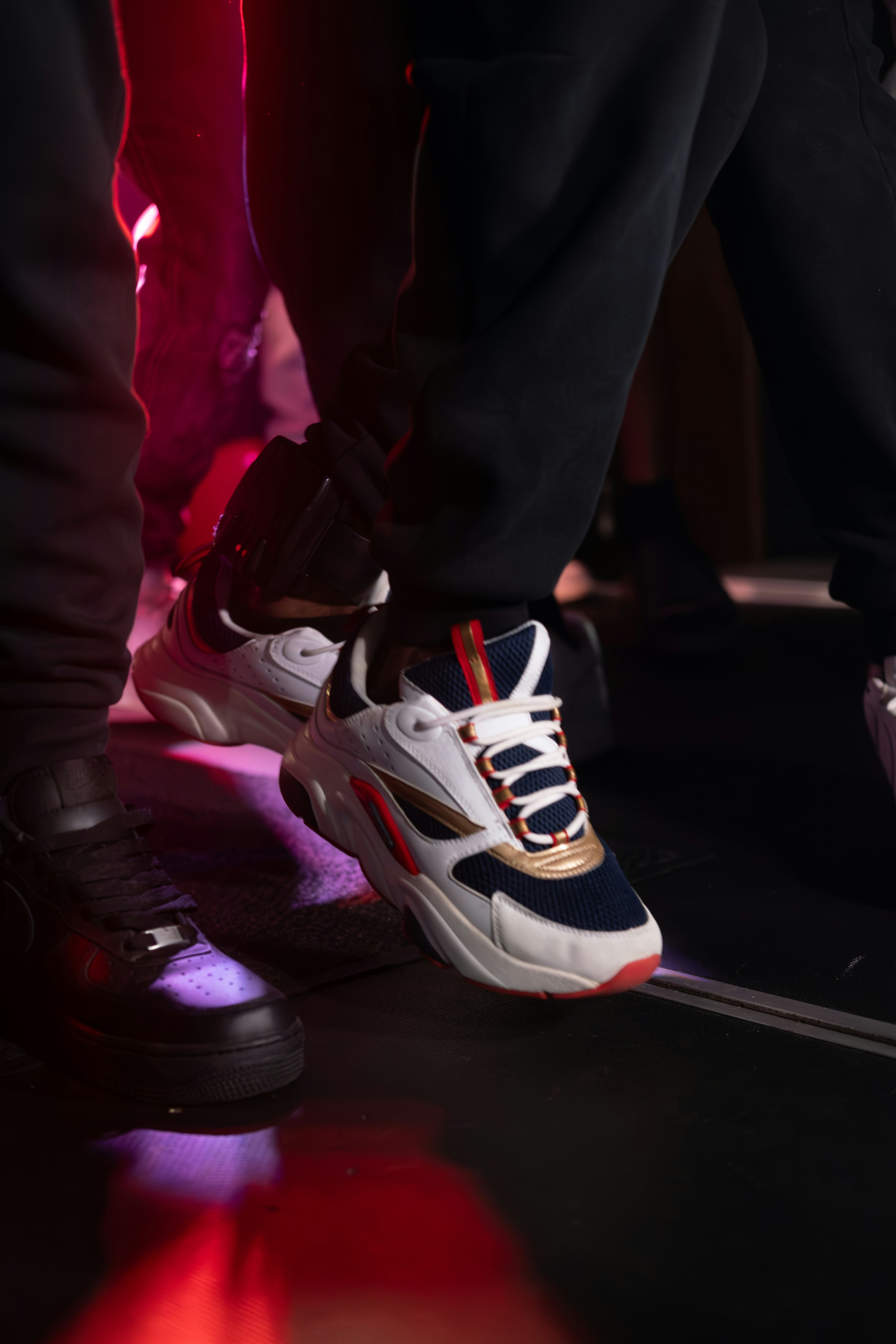 Bold red sneakers close-up on dark concrete, dramatic low-key studio lighting