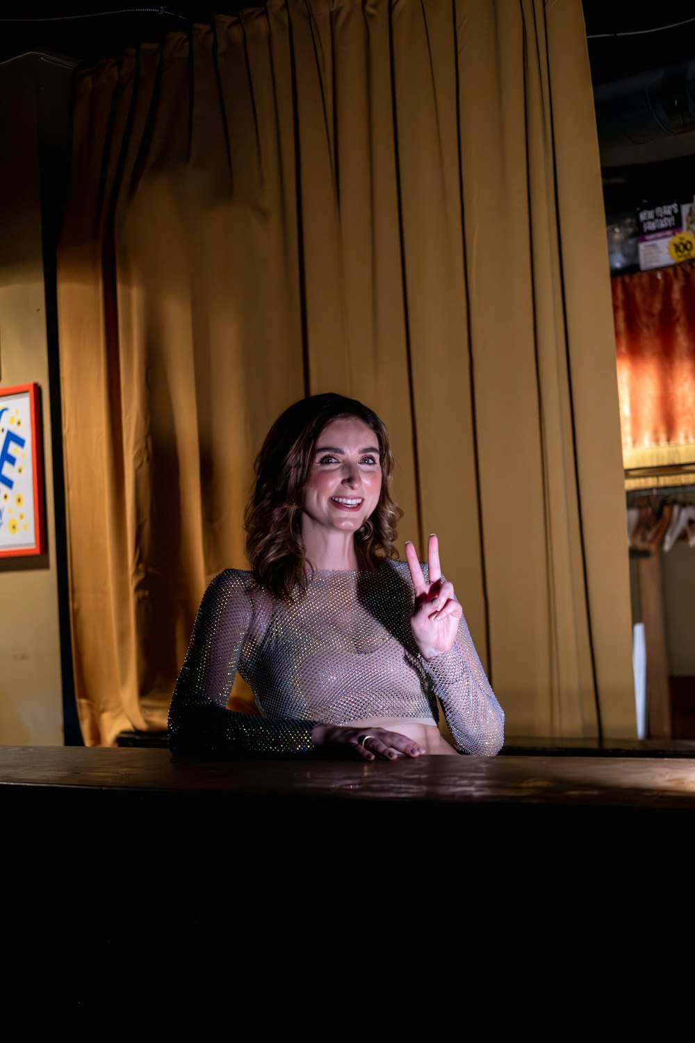 a woman sitting at a table making a peace sign