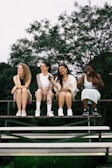 a group of women sitting on top of a wooden bench