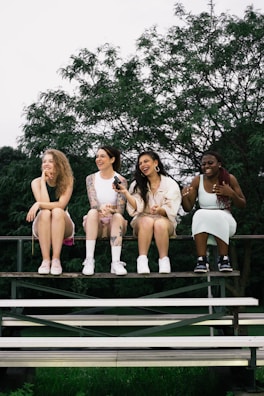 a group of women sitting on top of a wooden bench