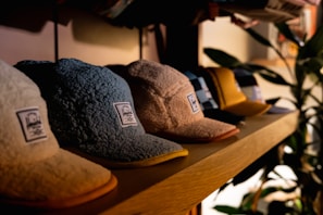 a row of hats sitting on top of a wooden shelf