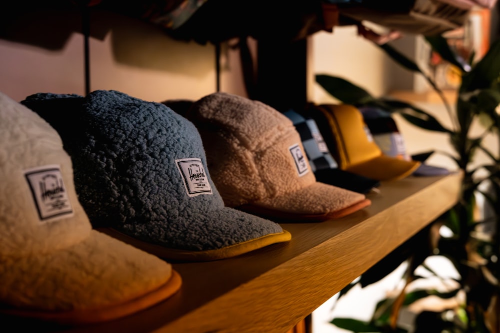 a row of hats sitting on top of a wooden shelf
