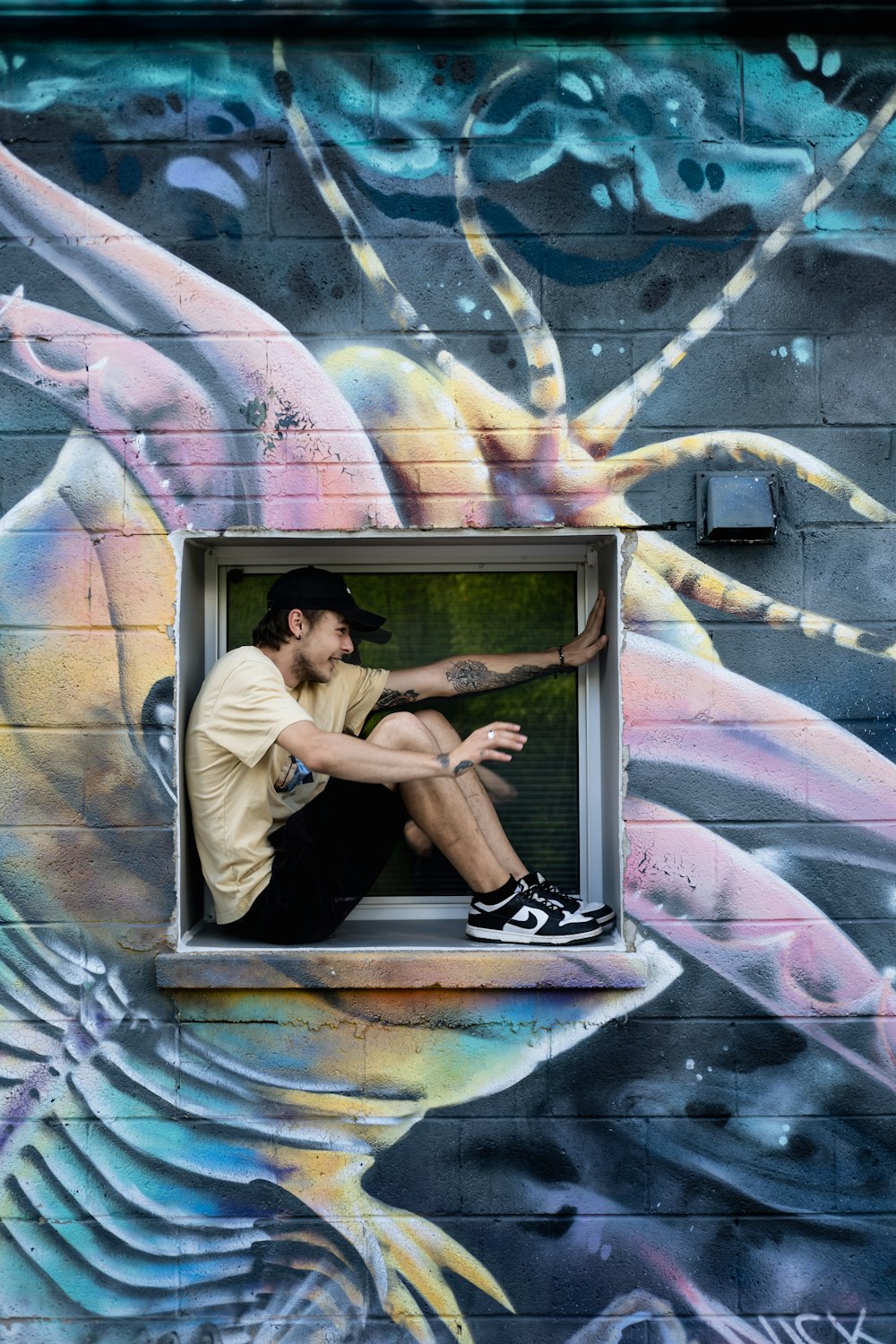 a man sitting on a window sill in front of a mural