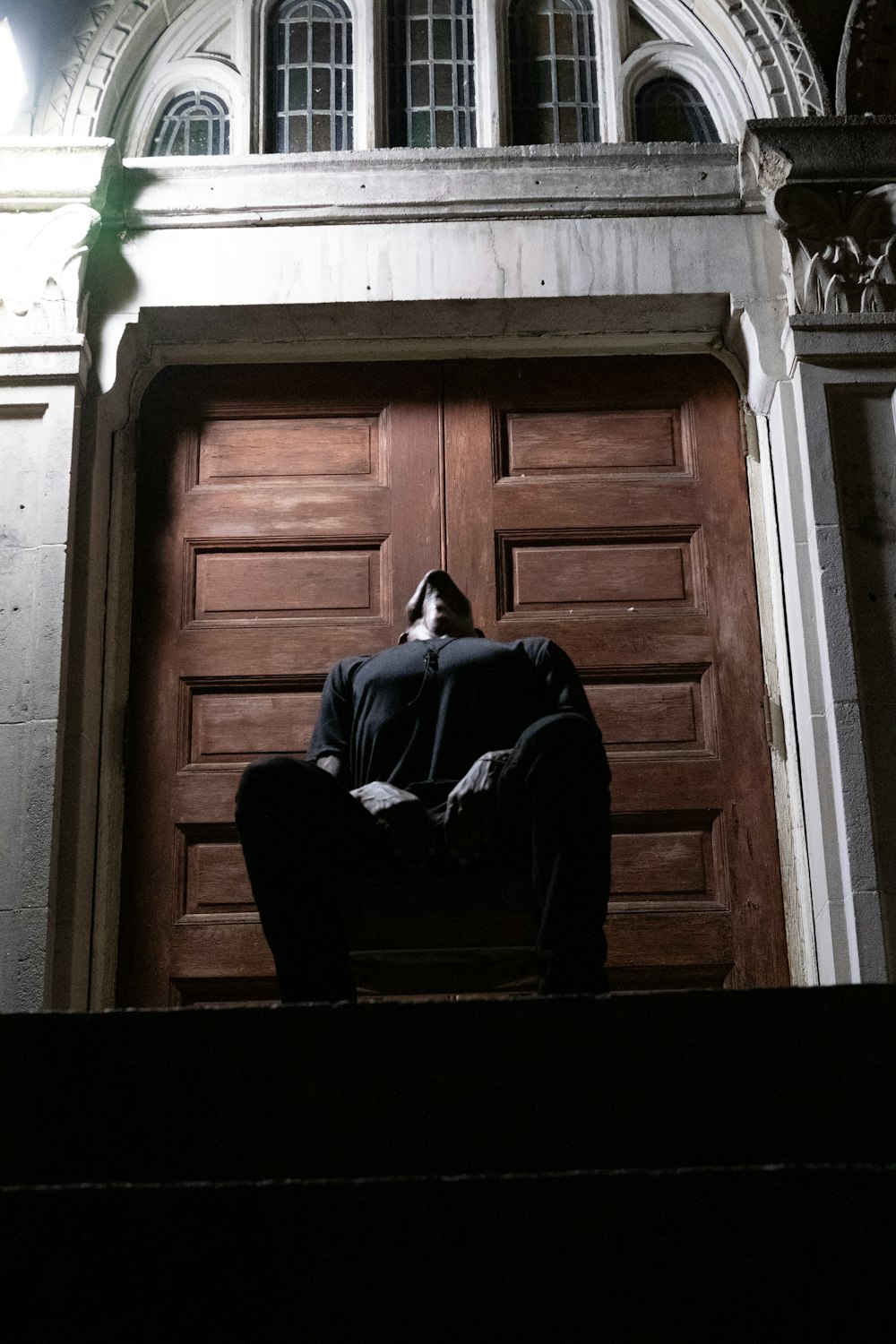 a man in a suit sitting on a bench in front of a door