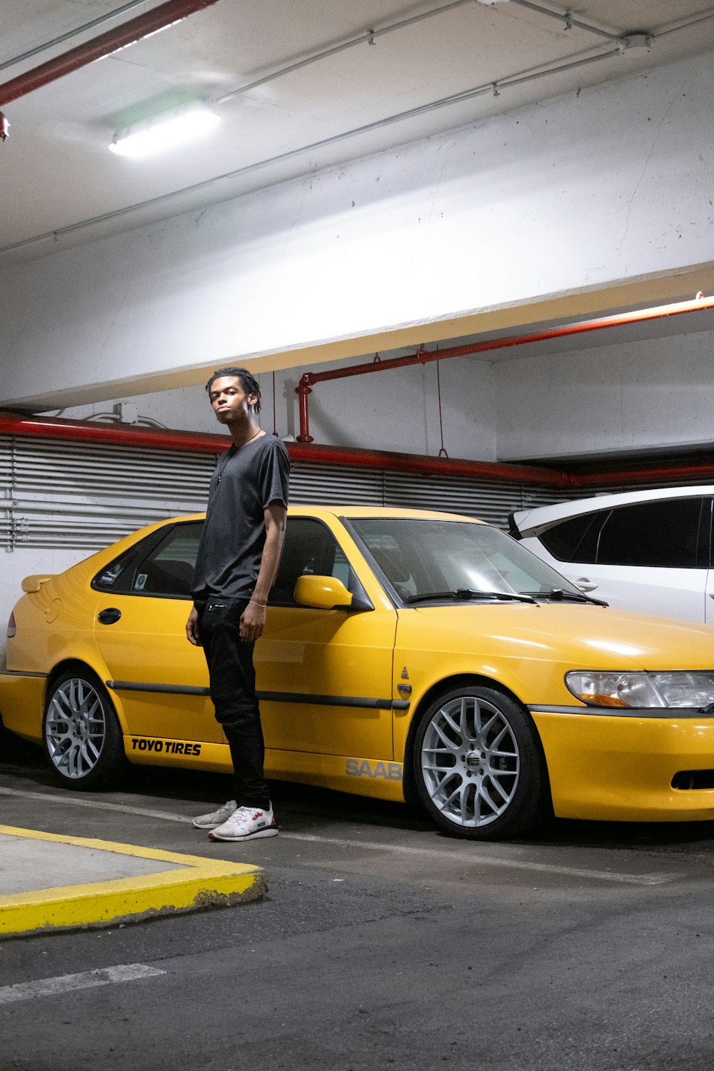 a man standing next to a yellow car in a parking garage