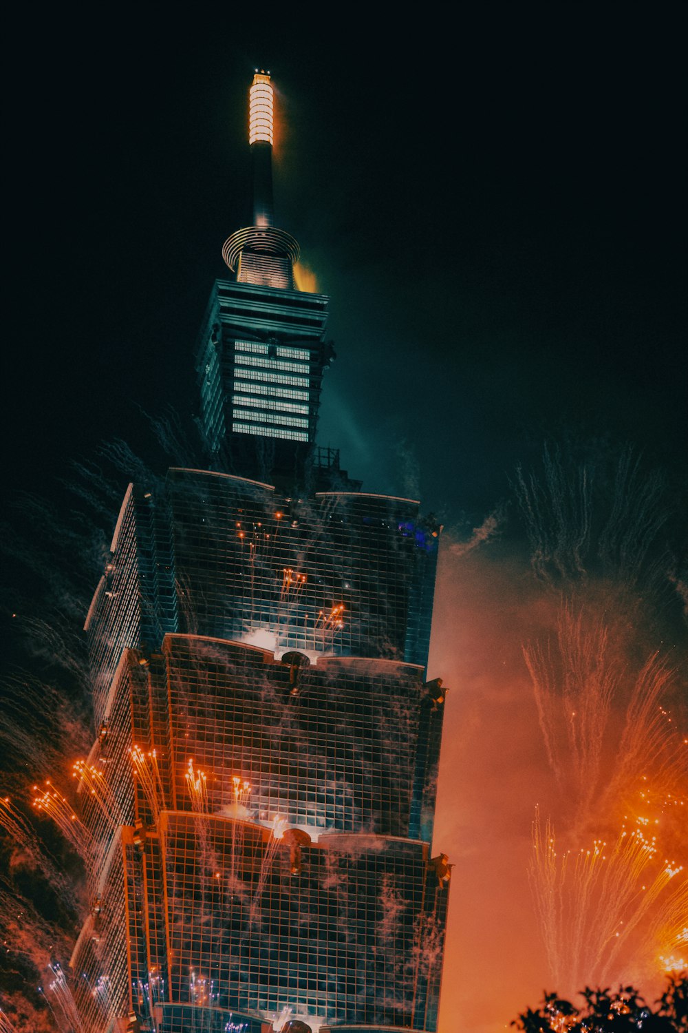 fireworks are lit up in the night sky above a skyscraper
