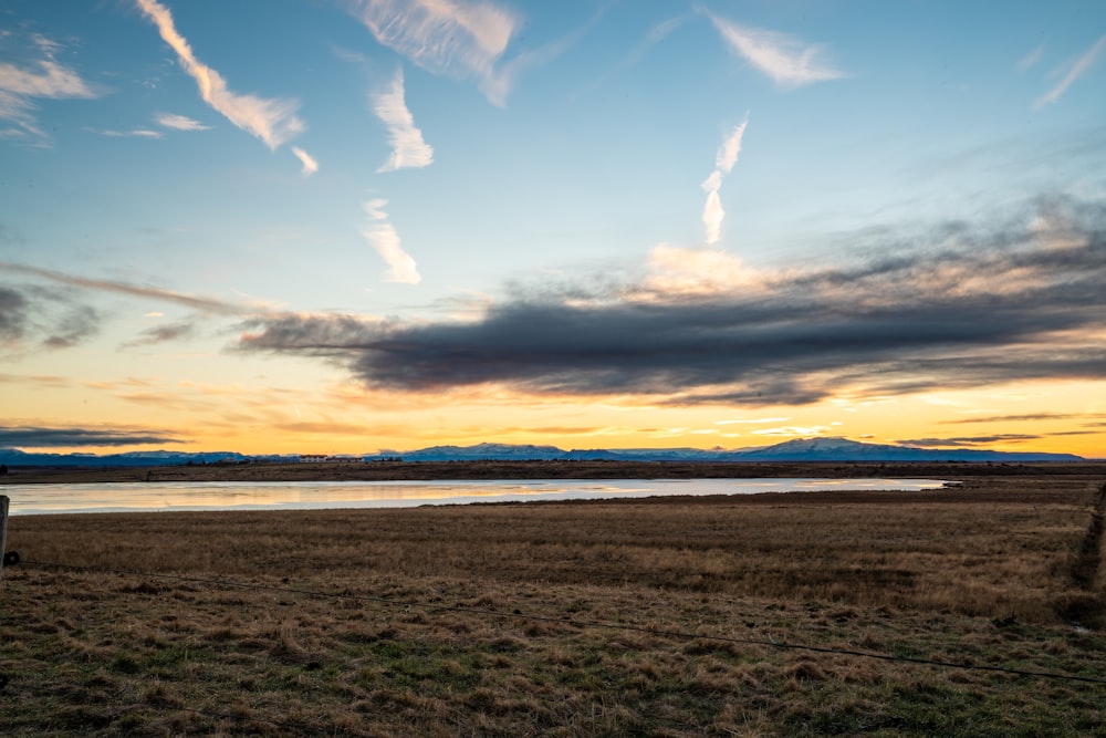 a grassy field with a body of water in the distance