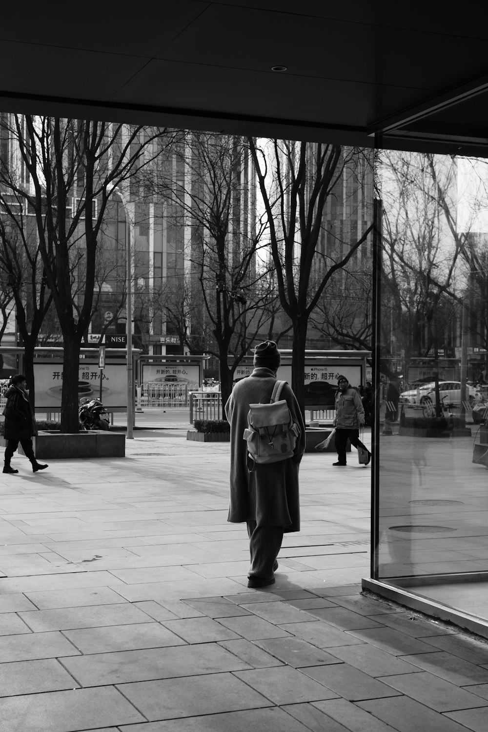 a man walking down a sidewalk next to a tall building