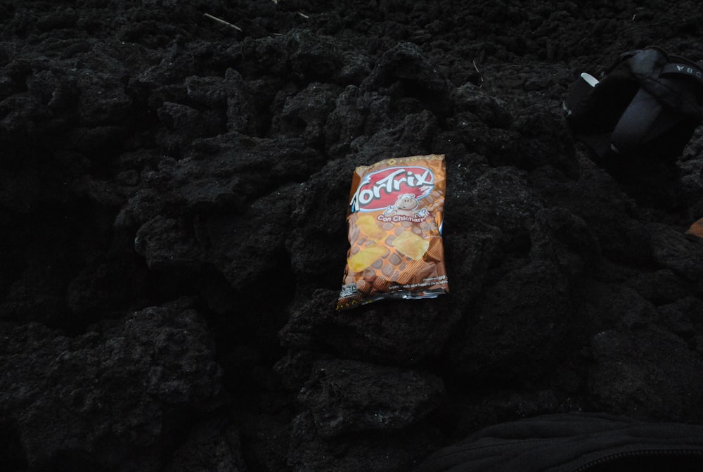 a bag of chips sitting on top of a pile of black rocks