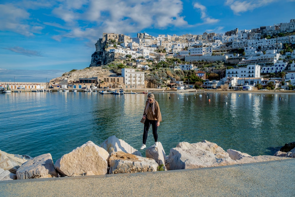 a man standing on a rock next to a body of water