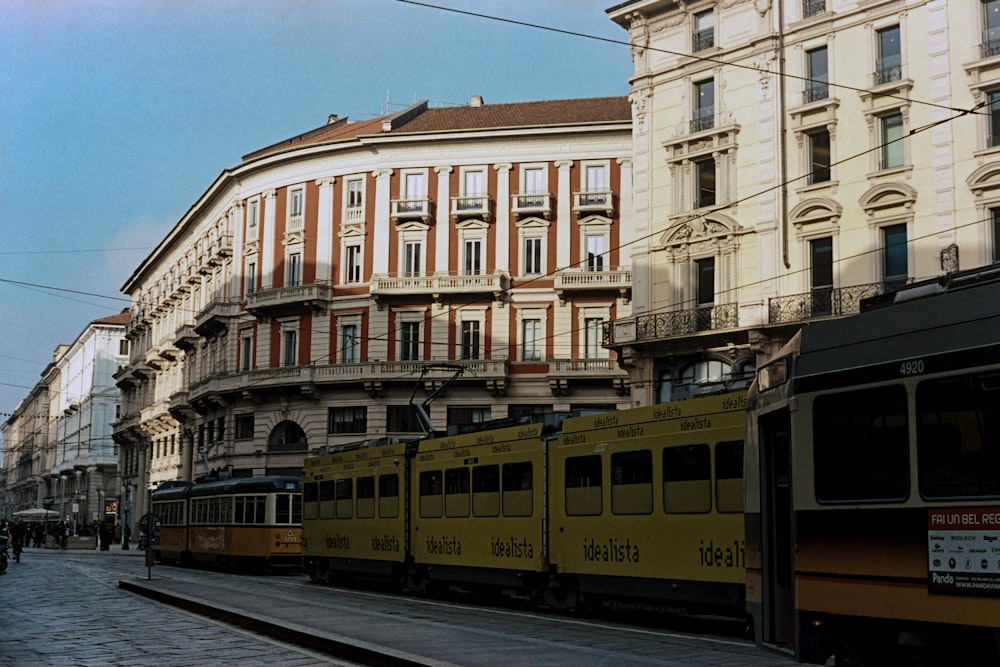 a yellow train traveling down train tracks next to tall buildings