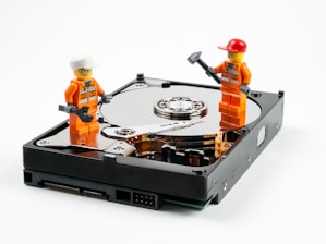 a couple of legos standing next to a hard drive