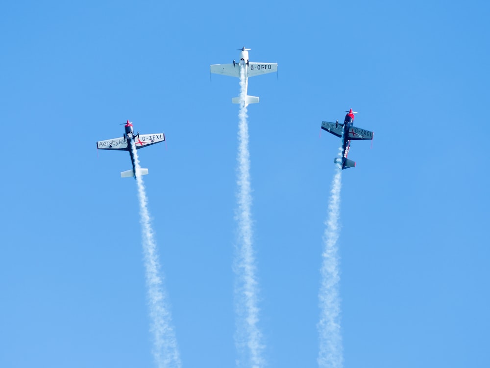 three airplanes flying in the sky with smoke coming out of them