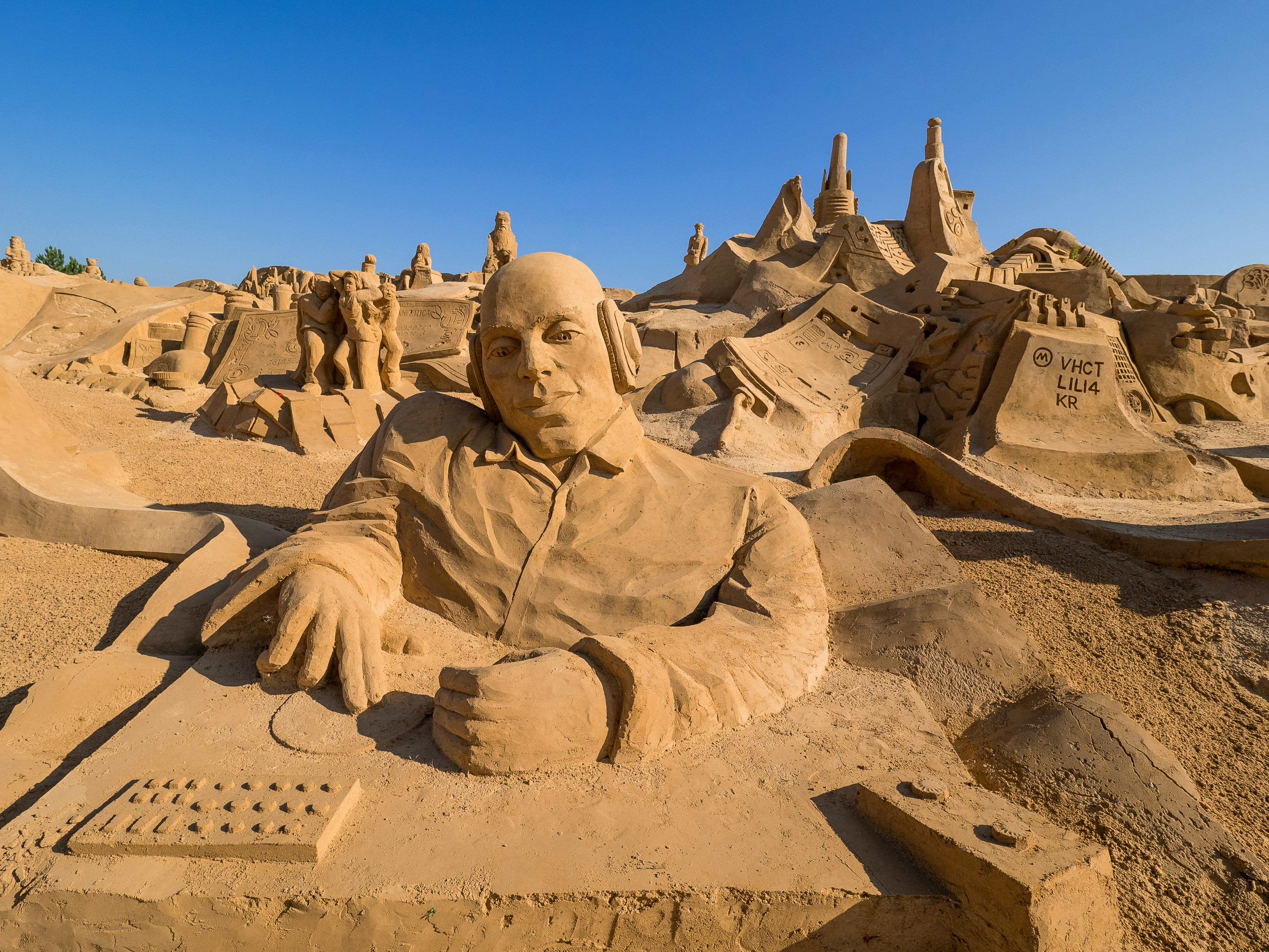 a sand sculpture of a man sitting in front of a computer, Sand Sculpture