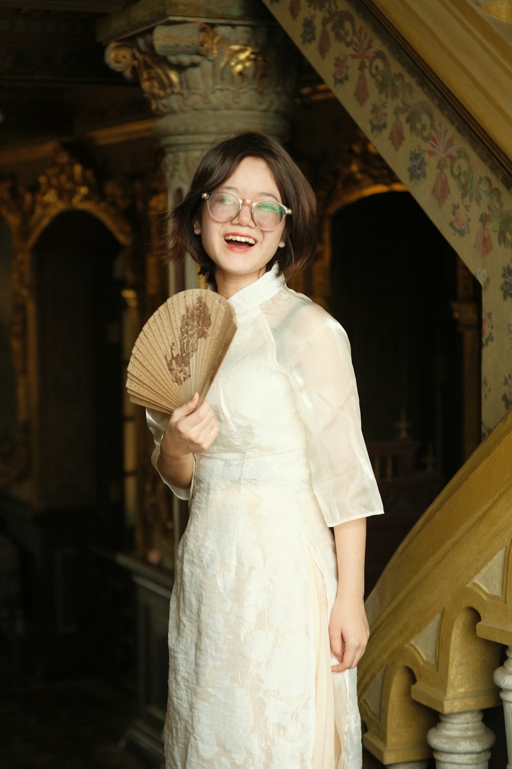 a woman in a white dress holding a fan